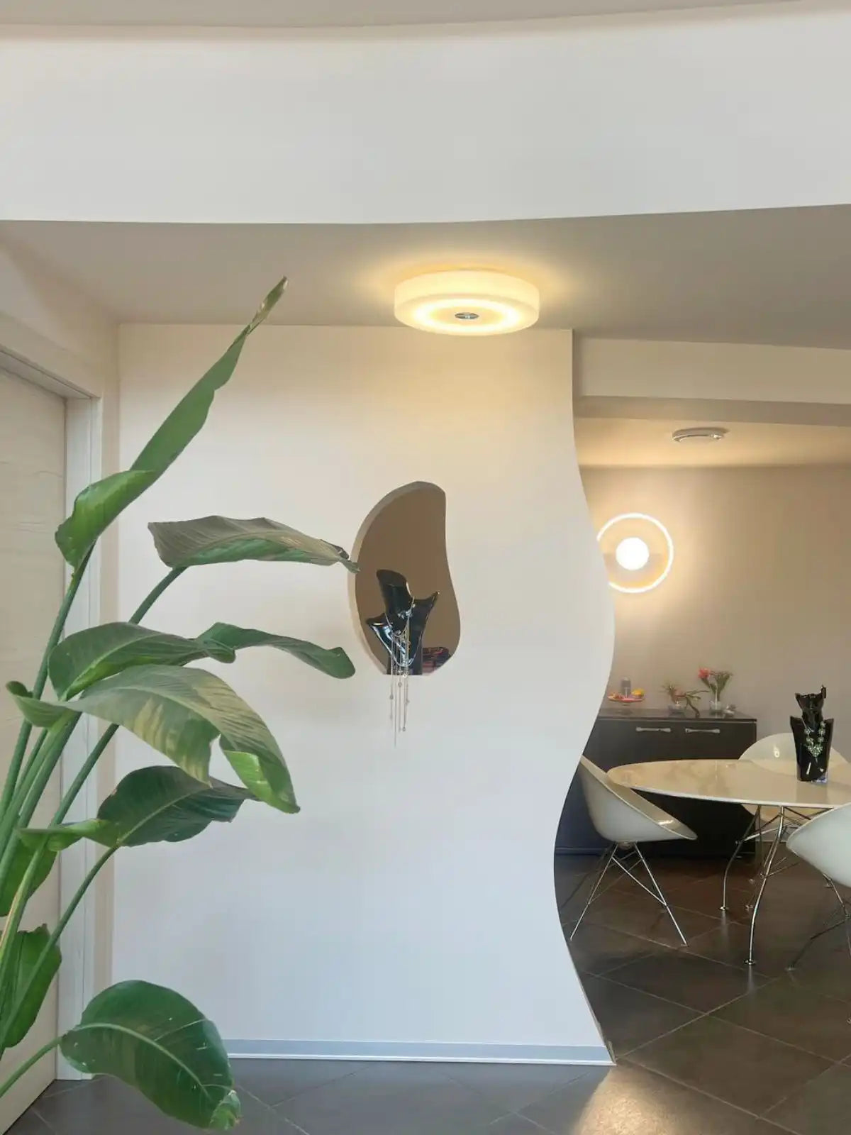 A unique, irregularly shaped wall mirror with a dark, reflective surface.