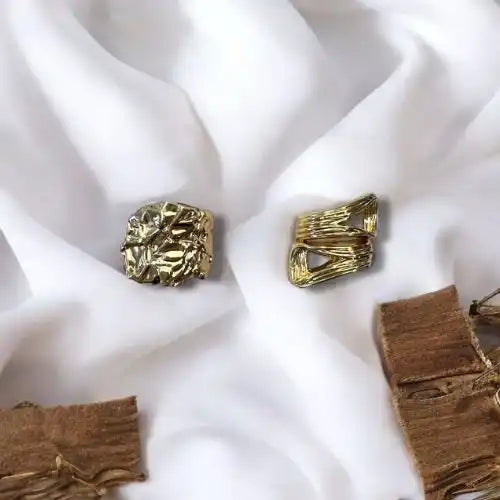 Two gold-colored rings with textured, abstract designs.